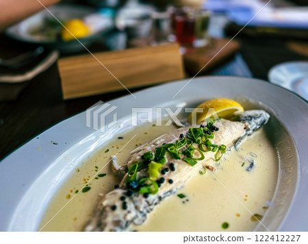 Fried Golden trout fish with lemon and herbs in a white plate on a wooden table at the restaurant in Ukraine 122412227