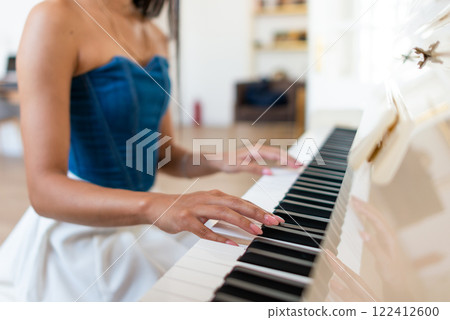 Woman playing the piano her hands are gracefully moving over the keys as she performs. 122412600