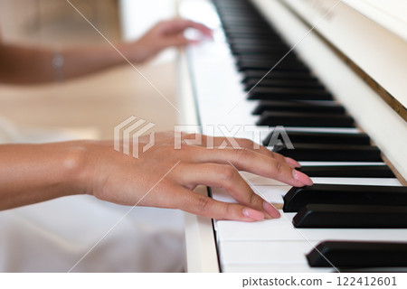Close-up of a female hands on the piano keys side view 122412601