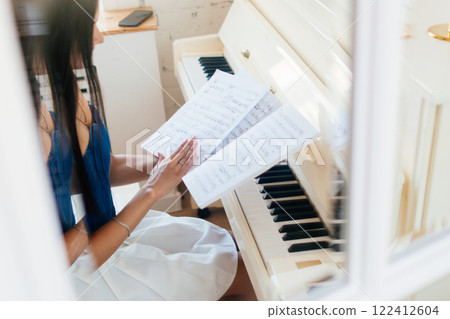 Female at the piano with a sheet music Female at the piano with a sheet music 122412604