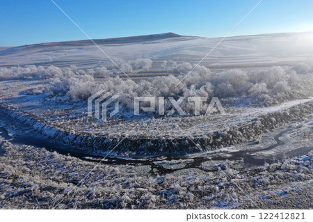Aerial view of snow-covered landscape with fog rolling over fields and hills in winter season 122412821