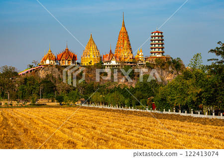 View of dry paddy field and Wat Tham Sua, the beautiful buddhist temple on top of the mountain. 122413074