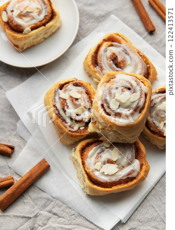 Delicious cinnamon rolls topped with icing and almonds on baking paper 122413571