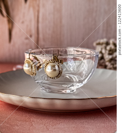 桌上玻璃碗邊緣掛著珍珠耳環 桌上玻璃碗邊緣掛著珍珠耳環 122413600