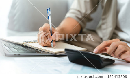 A man is using a calculator to calculate his income tax to fill out his annual income tax return A man is using a calculator to calculate his income tax to fill out his annual income tax return 122413808