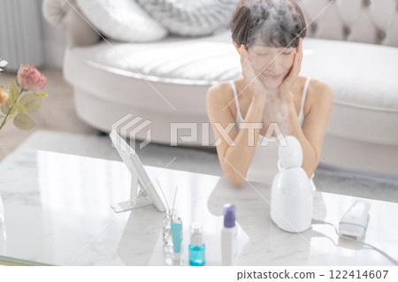 A middle-aged woman doing steam cleansing with a facial steamer A middle-aged woman doing steam cleansing with a facial steamer 122414607