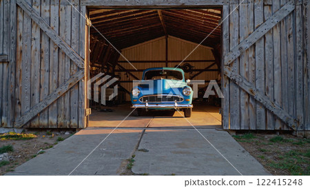 Vintage Car Parked in a Rustic Barn at Sunset, Showcasing Timeless Elegance and Charm 122415248