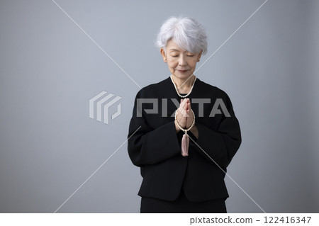 Senior woman wearing mourning clothes and praying Senior woman wearing mourning clothes and praying 122416347