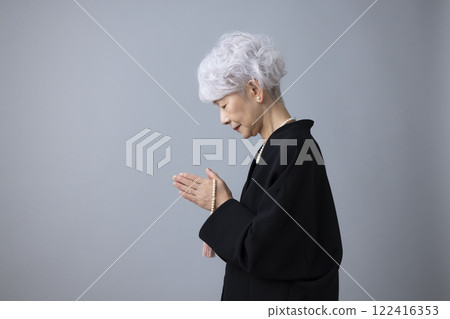 Senior woman wearing mourning clothes and praying 122416353
