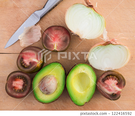 Vegetables black tomatoes, avocado and onions on wooden board Vegetables black tomatoes, avocado and onions on wooden board 122416592