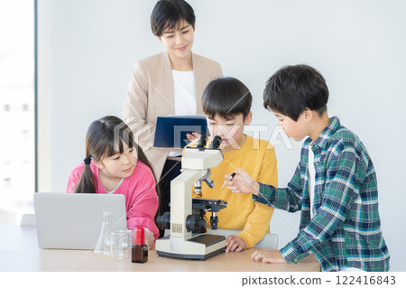 Elementary school students observing through a microscope 122416843