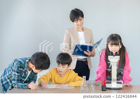 Elementary school students observing through a microscope 122416844