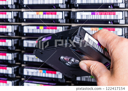 hand of a technician holding data storage magnetic tape in front 122417154