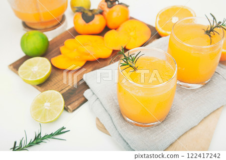 persimmon juice in a glass And there are orange slices and a blender all around. 122417242
