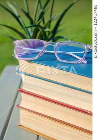 Glasses on stacked colorful books with a potted plant on a wooden table. High quality photo 122417465