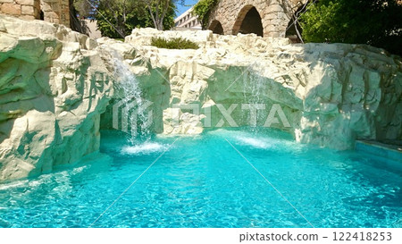 Luxurious hotel pool area with natural rock formations and lush landscaping in bright sunlight Luxurious hotel pool area with natural rock formations and lush landscaping in bright sunlight 122418253