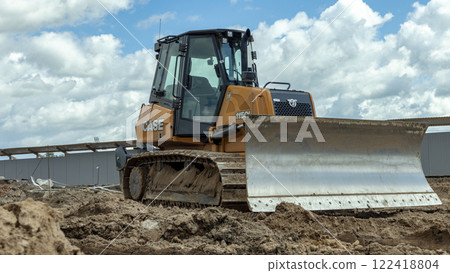 an orange bulldozer stands on a construction site with a lowered knife an orange bulldozer stands on a construction site with a lowered knife 122418804