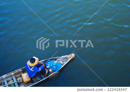 An Asian fisherman catches fish while sitting in a traditional boat. Vietnam. 122419347