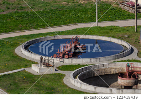 Modern wastewater treatment facility with circular tanks and equipment in open green area 122419439