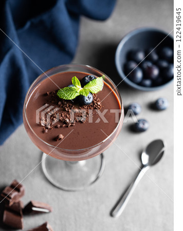 Chocolate pudding in a tall glass with mint and fresh blueberry on a dark background 122419645