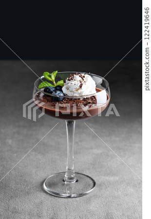 Chocolate pudding in a glass with whipped cream, fresh blueberries and mint on a dark background. Chocolate pudding in a glass with whipped cream, fresh blueberries and mint on a dark background. 122419646