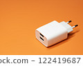 Power adapter with two USB ports without cable on orange background 122419687