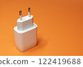 White power supply without cable on orange background. Power adapter, gadget charger 122419688