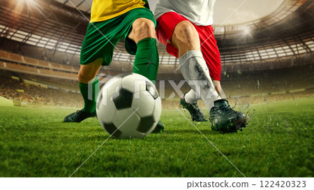 Soccer players uniforms competing for control of soccer ball on lush grass in stadium, spikes dig into turf as intensity increases. Soccer players uniforms competing for control of soccer ball on lush grass in stadium, spikes dig into turf as intensity increases. 122420323