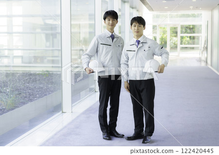 Portrait of two young men wearing work clothes standing in an aisle 122420445