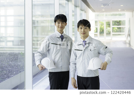 Portrait of two young men wearing work clothes standing in an aisle Portrait of two young men wearing work clothes standing in an aisle 122420446
