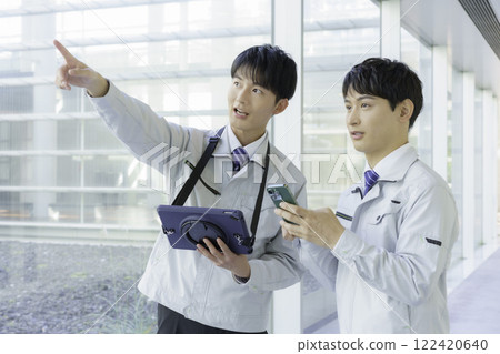 兩個穿著工作服的年輕人在走道上聊天 122420640