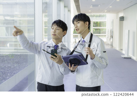Two young men wearing work clothes having a conversation in an aisle Two young men wearing work clothes having a conversation in an aisle 122420644
