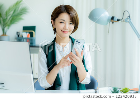 經營一部智能手機的女商人在辦公室 122420933