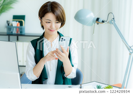經營一部智能手機的女商人在辦公室 122420934