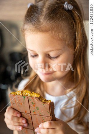 Little girl eating Dubai chocolate with pistachio paste and kataifi dough. Confectionery handmade sweets at home in the kitchen. Little girl eating Dubai chocolate with pistachio paste and kataifi dough. Confectionery handmade sweets at home in the kitchen. 122421030