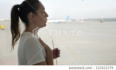 Woman breathing deeply at the airport holding boarding pass 122421279