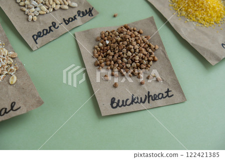 Refillable raw buckwheat porridge with text in paper examples. Refill product format eco-friendly living. Whole spelt grain species. High protein fiber-rich vegan plant based food ingredient. Gluten 122421385