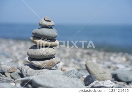 Smooth pebbles on the beach against the background of the sea and sunlight, creating a side effect on the water. Balancing rocks on a pebble beach during sunset. High quality photo Smooth pebbles on the beach against the background of the sea and sunlight, creating a side effect on the water. Balancing rocks on a pebble beach during sunset. High quality photo 122421435