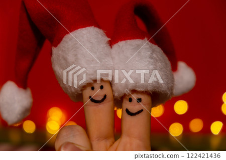 Fingers dressed in Santa-Claus red-white hats. Two happy finger smileys faces representing social network on red background. Copy space for your text Happy family celebrating concept for Christmas or Fingers dressed in Santa-Claus red-white hats. Two happy finger smileys faces representing social network on red background. Copy space for your text Happy family celebrating concept for Christmas or 122421436