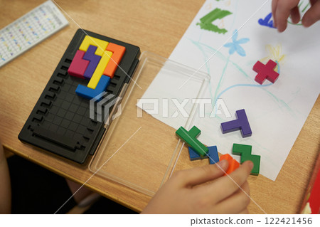 A plastic tetris game. Leisure time for children on vacation. An unrecognizable child is playing a plastic-based puzzle game. With space to copy. High quality photo A plastic tetris game. Leisure time for children on vacation. An unrecognizable child is playing a plastic-based puzzle game. With space to copy. High quality photo 122421456