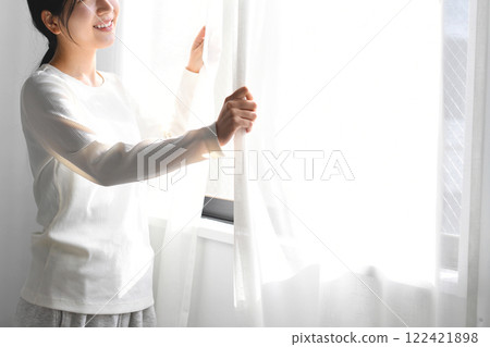 Asian woman opening the curtains and basking in the sunlight 122421898