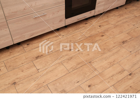 Empty place for Carpet, Mat or text. Top view. Ceramic Wood Floor Tiles on Kitchen, Walnut Ceramic Floor. Beige Furniture at Kitchen. Empty place for Carpet, Mat or text. Top view. Ceramic Wood Floor Tiles on Kitchen, Walnut Ceramic Floor. Beige Furniture at Kitchen. 122421971
