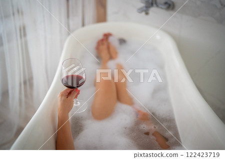 Close-up of female legs with red shoes and glass of wine 122423719