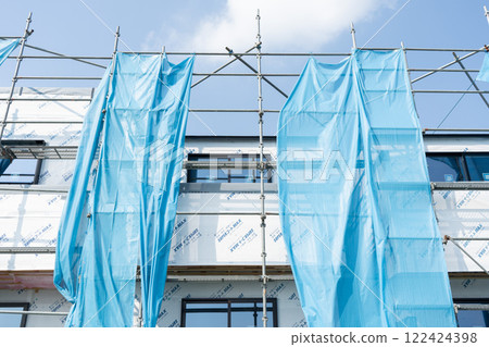 Applying moisture-permeable waterproof sheets to three prefabricated houses under construction 122424398