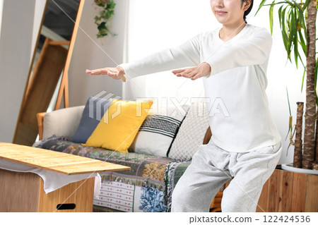 A woman doing bodyweight training (squats) at home A woman doing bodyweight training (squats) at home 122424536