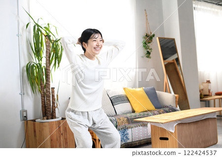 A woman doing bodyweight training (squats) at home 122424537
