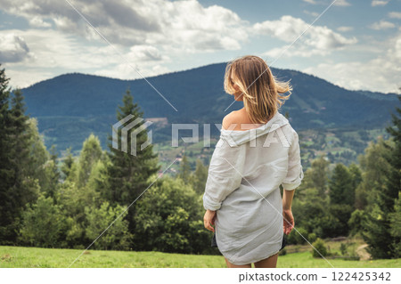 Young woman in white shirt on the background of mountains and blue sky Young woman in white shirt on the background of mountains and blue sky 122425342
