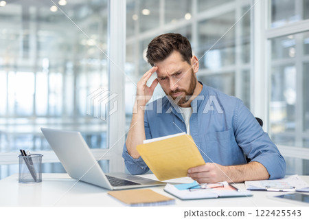 Bad news mail message about bankruptcy. Man upset inside office disappointed reading notification, holding envelope with letter. Dissatisfied worker inside office at workplace. Bad news mail message about bankruptcy. Man upset inside office disappointed reading notification, holding envelope with letter. Dissatisfied worker inside office at workplace. 122425543