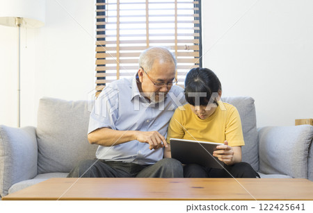 Old senior asian grandparent play and watch computer tablet with grandchildren girl at home. Bonding relationship in family.  122425641