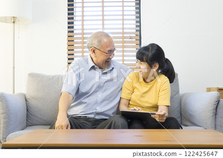Old senior asian grandparent play and watch computer tablet with grandchildren girl at home. Bonding relationship in family.  122425647